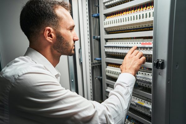 Man system administrator pressing on electrical switch